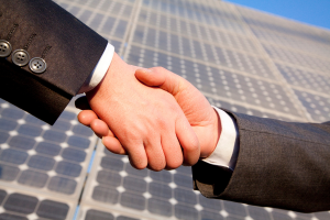 Zwei Hände im Handschlag vor Solarpanels