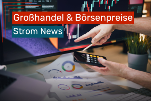 Person arbeitet am Schreibtisch an Finanzcharts auf einem Monitor und nutzt dabei Smartphone-Taschenrechner und ausgedruckte Diagramme.